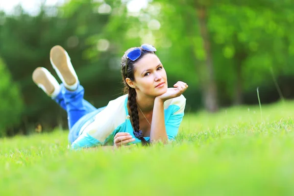 Young pretty woman lying on the grass at summer sunset — Stock Photo, Image