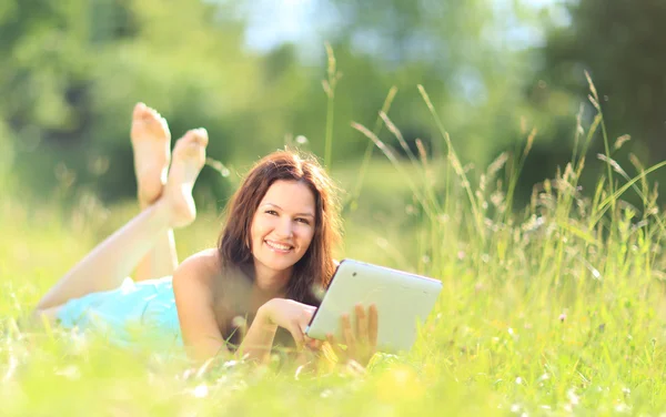 Mujer feliz leyendo e-book en el parque —  Fotos de Stock