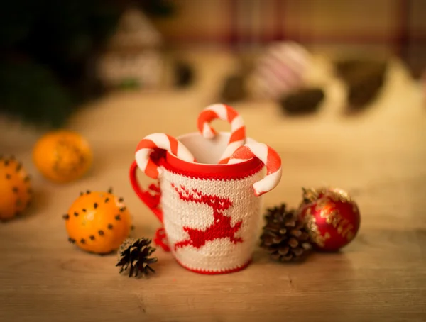 Insulated wool cloth mug with embroidered deer on the wooden table mug with tangerines and a candy