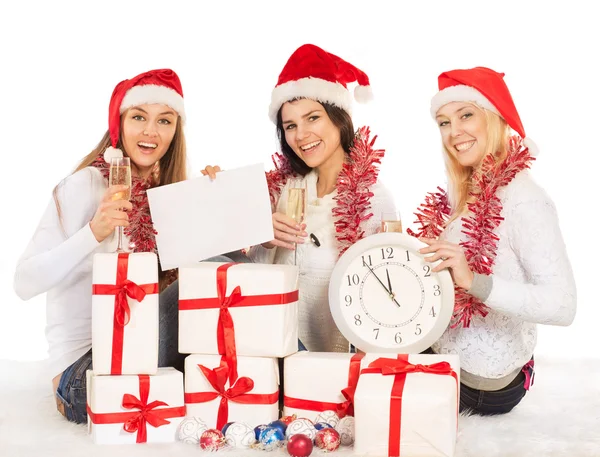 Three beautiful girls on the New Year's Eve sit with clock, gifts, champagne — Stock Photo, Image