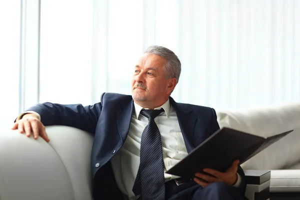 Businessman in office with a folder sits and works — Stock Photo, Image