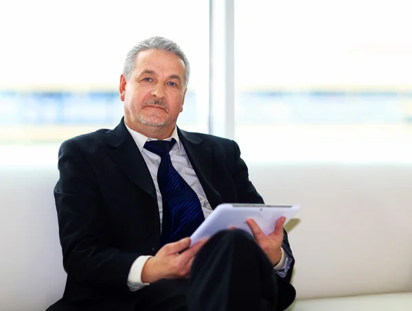 Businessman in office with the tablet sits and works — Stock Photo, Image