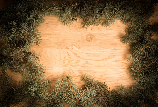 Green fir branches on the wooden floor with darkening at the edges — Stock Photo, Image