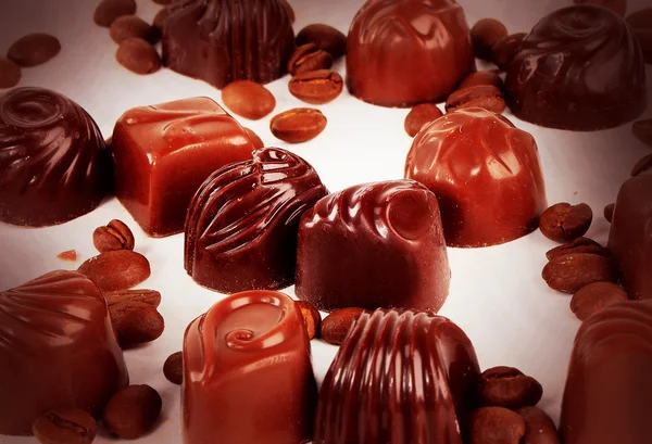 Doces de chocolate doce e grãos de café isolados em fundo branco — Fotografia de Stock