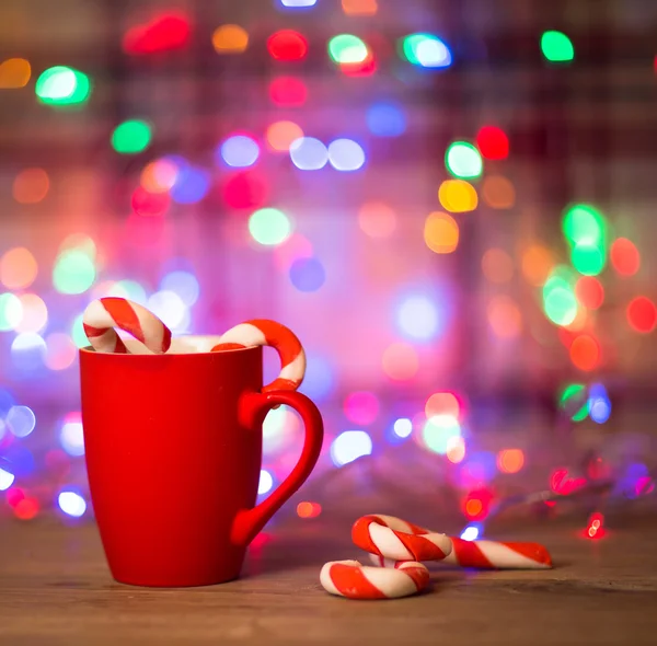 Tasse Tee oder Kaffee. Süßigkeiten. Weihnachtsdekoration. rote Kugeln und Glocken. hölzerner Hintergrund. — Stockfoto