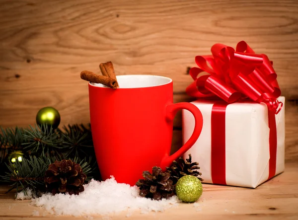 Mug Of Tea Or Coffee. Sweets And Spices. Christmas Decorations. Wooden Background. A gift with a red ribbon.