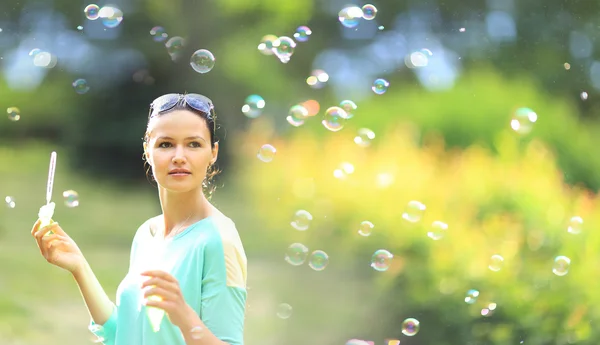 Krásná mladá dívka vyfukuje bubliny venku — Stock fotografie