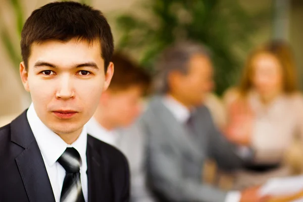 Feliz hombre de negocios inteligente con compañeros de equipo discutiendo en segundo plano — Foto de Stock