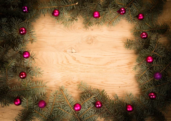 Green fir branches on the wooden floor with darkening at the edges with Christmas balls — Stock Photo, Image