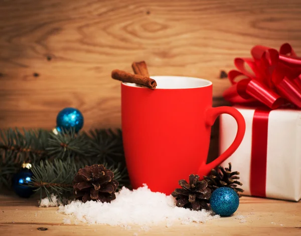 Mug Of Tea Or Coffee. Sweets And Spices. Christmas Decorations. Wooden Background. A gift with a red ribbon. — Stock Photo, Image