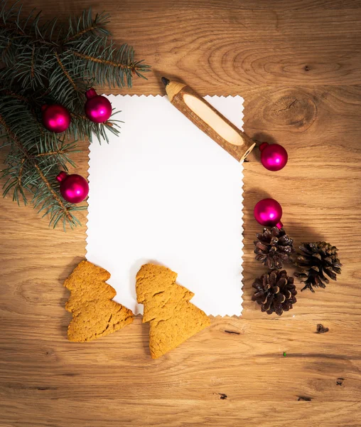 Ahşap zeminde boş bir kağıt tabaka. Kalem ve Noel süslemeleri ile birlikte. — Stok fotoğraf