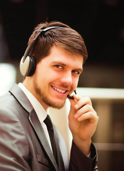 Joven feliz trabajando en el centro de llamadas, usando auriculares — Foto de Stock