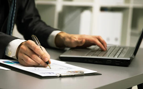 Close up of male hands doing paperwork with pen and laptop. — Stock Photo, Image