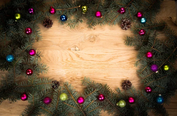Branches de sapin vert sur le sol en bois avec assombrissement sur les bords avec des boules de Noël — Photo