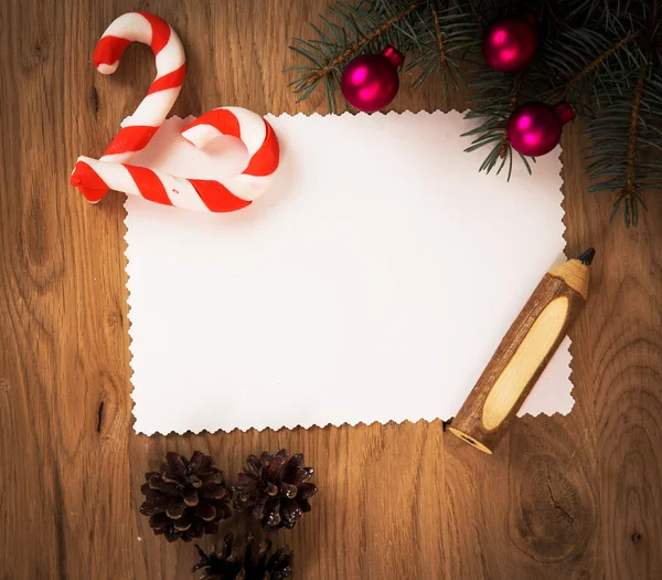 Hoja de papel en blanco en el suelo de madera con un lápiz y decoraciones de Navidad —  Fotos de Stock