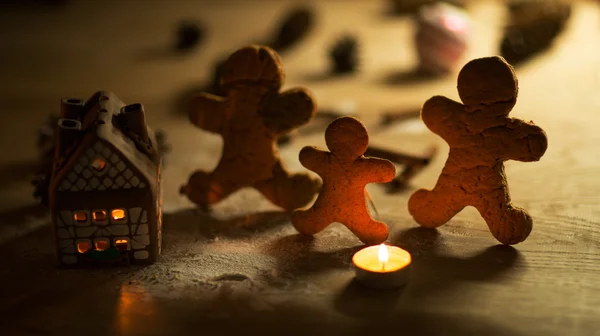 Christmas gingerbread men candles with cinnamon stars Pine twig Christmas ball on a wooden floor — Stock Photo, Image