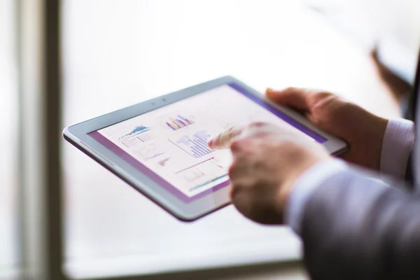 Бізнесмен аналізує фінансову статистику, відображену на екрані планшета — стокове фото