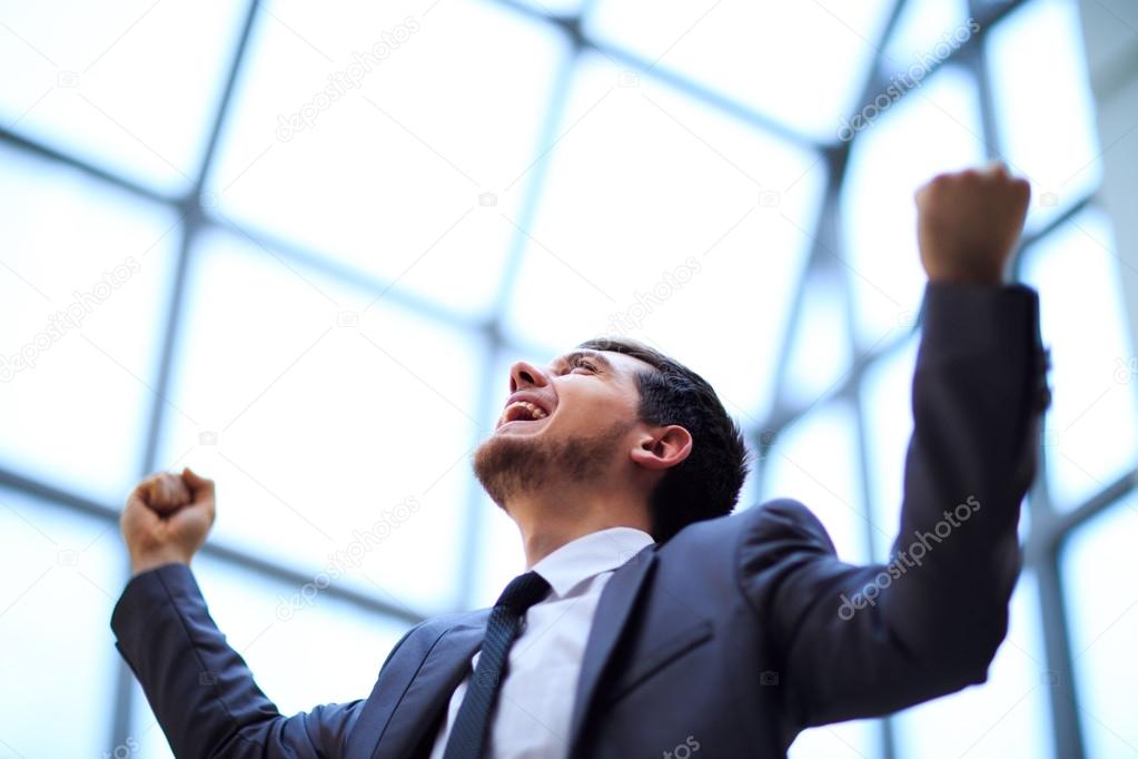 Successful businessman with arms up celebrating his victory