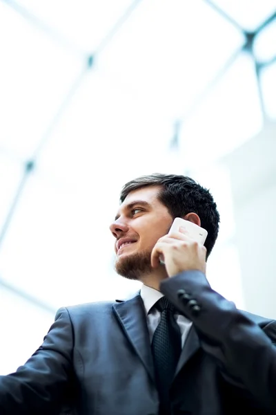 Jovem homem de negócios falando no telefone celular no escritório moderno — Fotografia de Stock