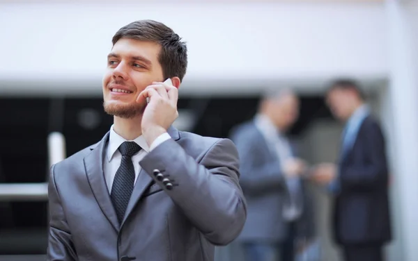 Empresário de pé dentro do edifício de escritórios moderno falando em um telefone celular — Fotografia de Stock