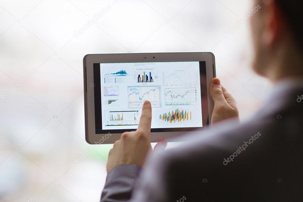 Business person analyzing financial statistics displayed on the tablet screen