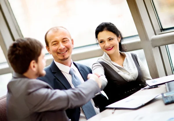 Uomo d'affari maturo che stringe la mano per concludere un accordo con il suo partner e colleghi in un ufficio moderno — Foto Stock