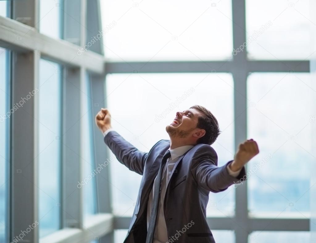 Successful businessman with arms up celebrating his victory