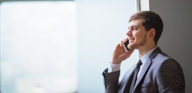 Modern ofiste cep telefonuyla konuşan genç bir iş adamı.