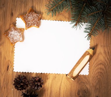 Ahşap zeminde boş bir kağıt tabaka. Kalem ve Noel süslemeleri ile birlikte.