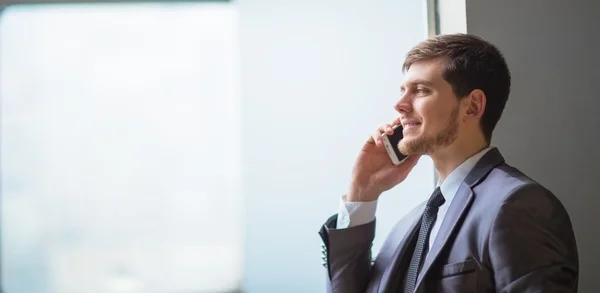 Ung affärsman pratar i mobiltelefon på modernt kontor — Stockfoto