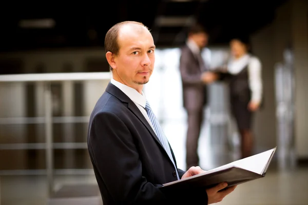 Felice uomo d'affari intelligente con i compagni di squadra discutendo in background — Foto Stock