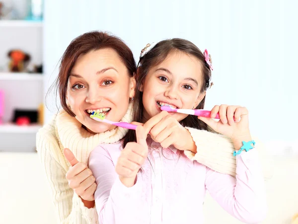 Mother and daughter brush their teeth. — Stock Photo, Image