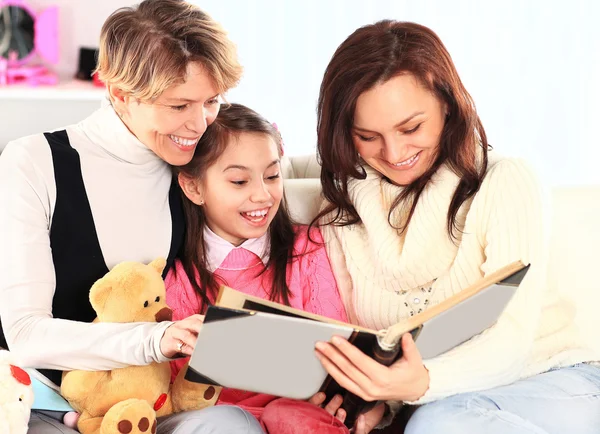 Grandmother, mother, and daughter reading a book together — Stock Photo, Image