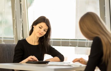 Ofiste bir masada oturuyor, bir hesap makinesi kullanarak, gülümseyen, iş arkadaşları, çalışan genç kadınlar