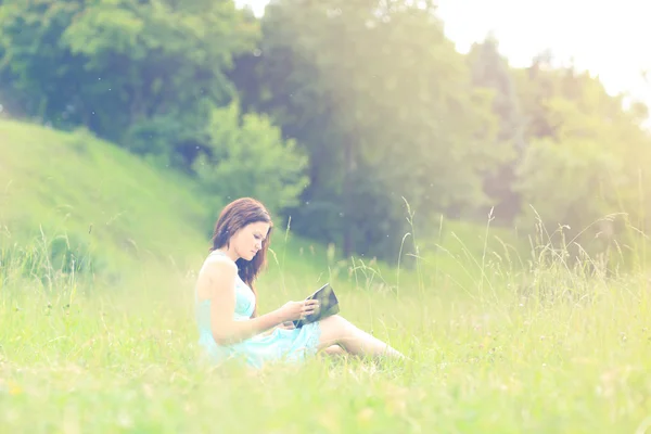 Chica sentada leyendo un libro al aire libre a la luz del sol —  Fotos de Stock