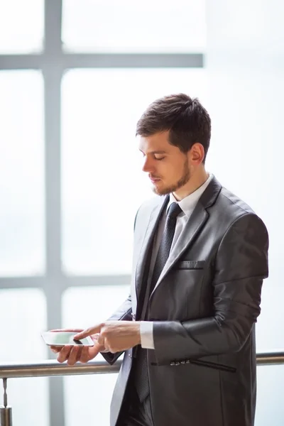 Joven hombre de negocios hablando por teléfono celular en la oficina moderna —  Fotos de Stock