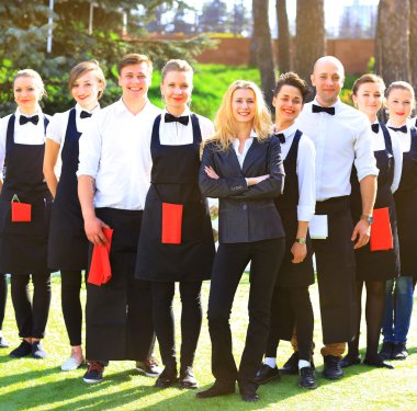 Large group of waiters and waitresses standing in row. clipart