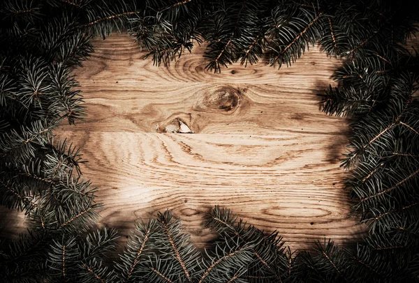 Green fir branches on the wooden floor with darkening at the edges — Stock Photo, Image