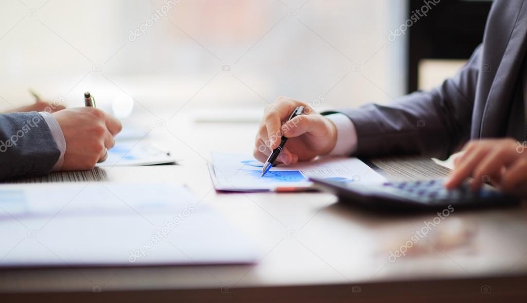 Two business people working sitting at the table. Close up of hands