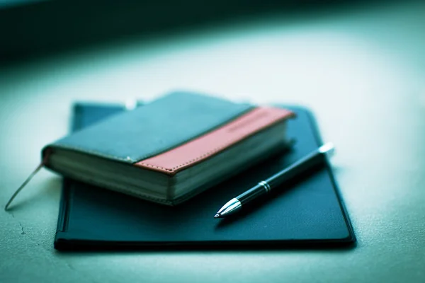 Notitieboekje met pen op tafel — Stockfoto