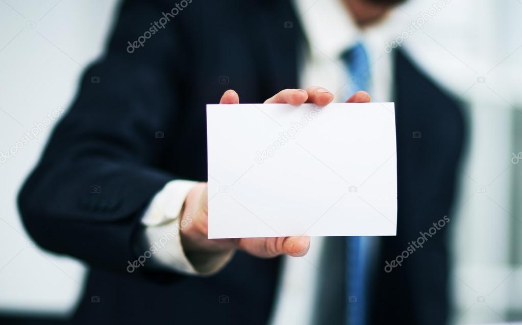 Man's hand showing business card - closeup shot on grey background
