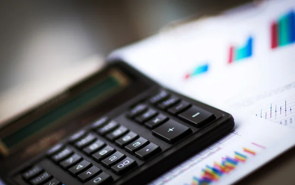Calculator met zakelijke tabellen, grafieken, informatie en verslagen achtergrond voor financiële en zakelijke concepten — Stockfoto