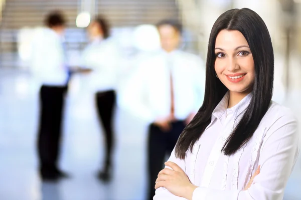 Mujer de negocios con su personal, grupo de personas en segundo plano en la oficina brillante moderna — Foto de Stock