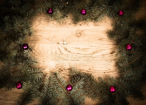 Ramas de abeto verde en el suelo de madera con oscurecimiento en los bordes con bolas de Navidad — Foto de Stock