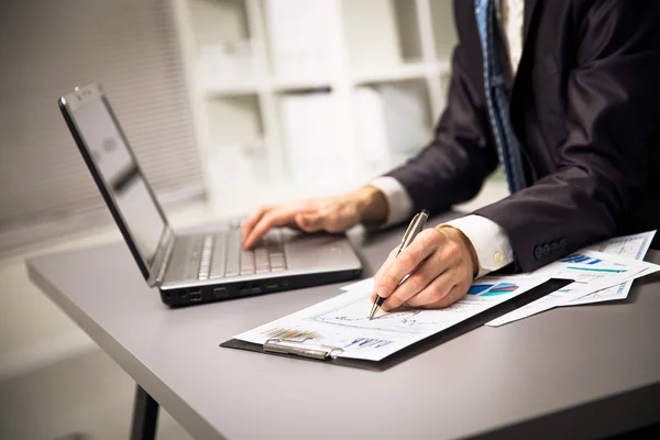 Närbild på manliga händer göra pappersarbete med penna och laptop. — Stockfoto