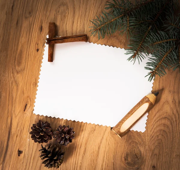 Чистый лист бумаги на деревянном полу с карандашом и рождественскими украшениями — стоковое фото