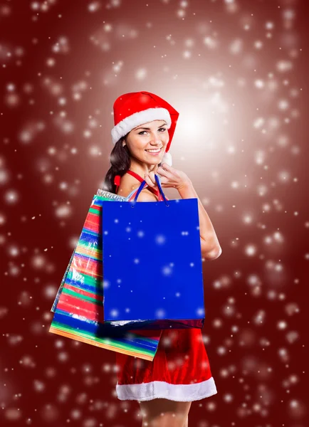 Menina bonita em traje de Papai Noel com compras — Fotografia de Stock