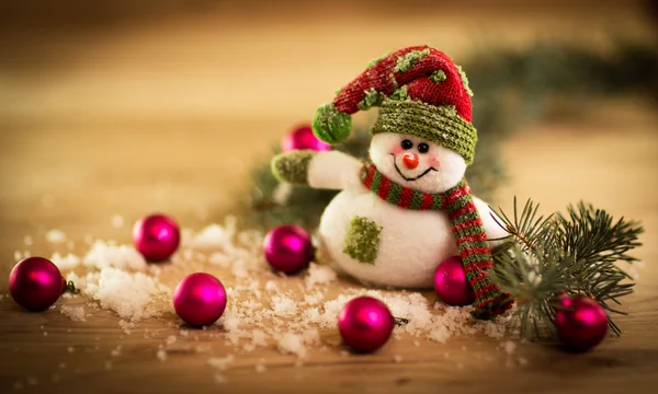 Vánoční pozadí s vánoční stromeček a sněhulák na rustikální dřevěné desce — Stock fotografie