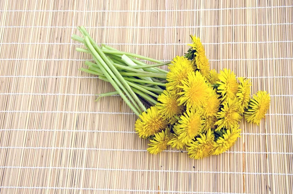 Bouquet of fresh dandelions on bamboo mat — Stock Photo, Image