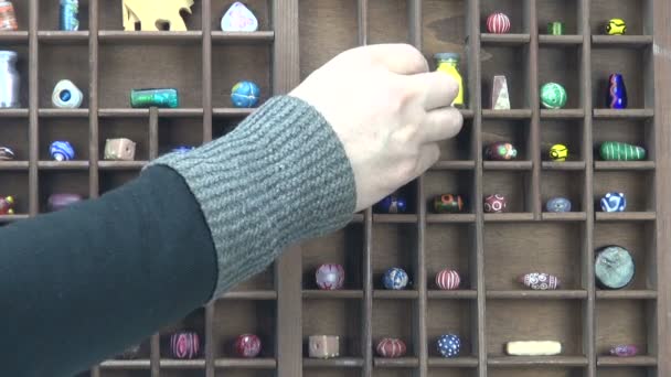 Hand  placing ceramic beads and paint bottles in shelf — Stock Video